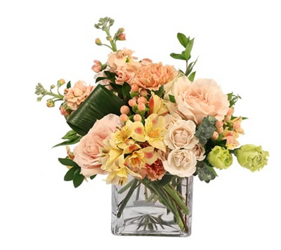 Timelessly Tranquil floral arrangement with peach roses, yellow alstroemeria, and greenery in a glass vase.