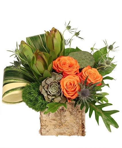 Floral arrangement with orange roses, succulents, and greenery in a rustic wooden vase.