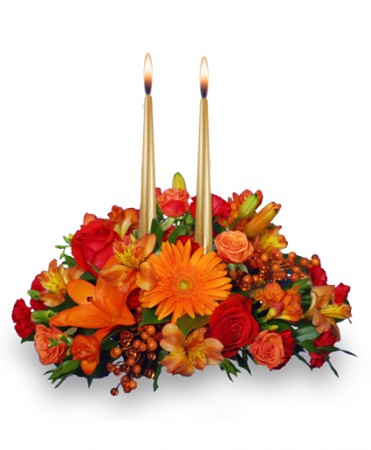 Fall floral centerpiece with orange roses, gerbera daisies, and two taper candles.